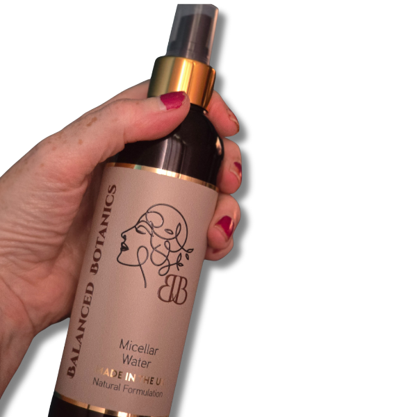 Hand holding a bottle of Balanced Botanics micellar water against a white background