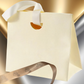 Beige gift bag with a ribbon on a gradient background